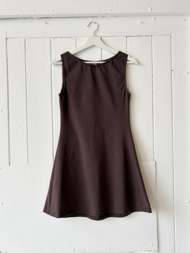 Brown dress hanging on a white wooden panel wall